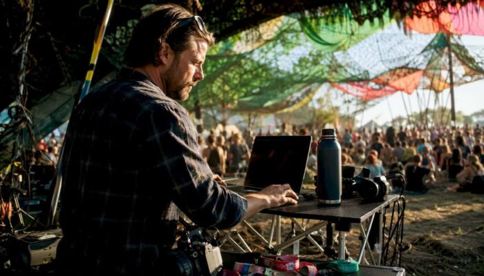 Filmmaker editing footage outdoors at music festival