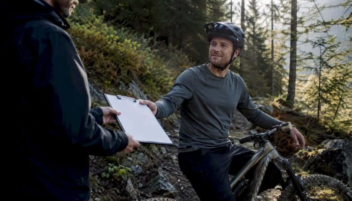Photographer giving model release form to biker outdoors